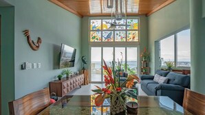 A spacious living room with a large window, a wooden ceiling, and a modern sofa.