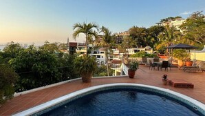 A rooftop pool area with a view of surrounding buildings, potted plants, and outdoor furniture. - Beautiful Vallarta View Condo*********** (Puerto Vallarta)
