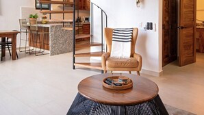 A modern interior with a spiral staircase, a round wooden table with remote controls, and a chair with a striped pillow. - Beautiful Vallarta View Condo*********** (Puerto Vallarta)