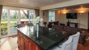 A spacious living area with a large island, a sofa, and a television. - The Coach House (Scarborough)