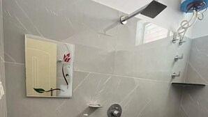 A bathroom with a marble sink, a handheld showerhead, and a wall-mounted faucet. - Rangi Taranga (Chikkamagaluru)