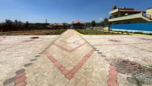 A paved walkway leading to a building with a blue exterior and a red roof. - Rangi Taranga (Chikkamagaluru)