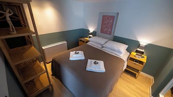 A bedroom with a bed, bedside tables, a nightstand, a shelf with a mannequin, and a wall art piece.