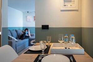 Une pièce comprenant une table à manger dressée pour deux personnes, un canapé et un luminaire fixé au mur.