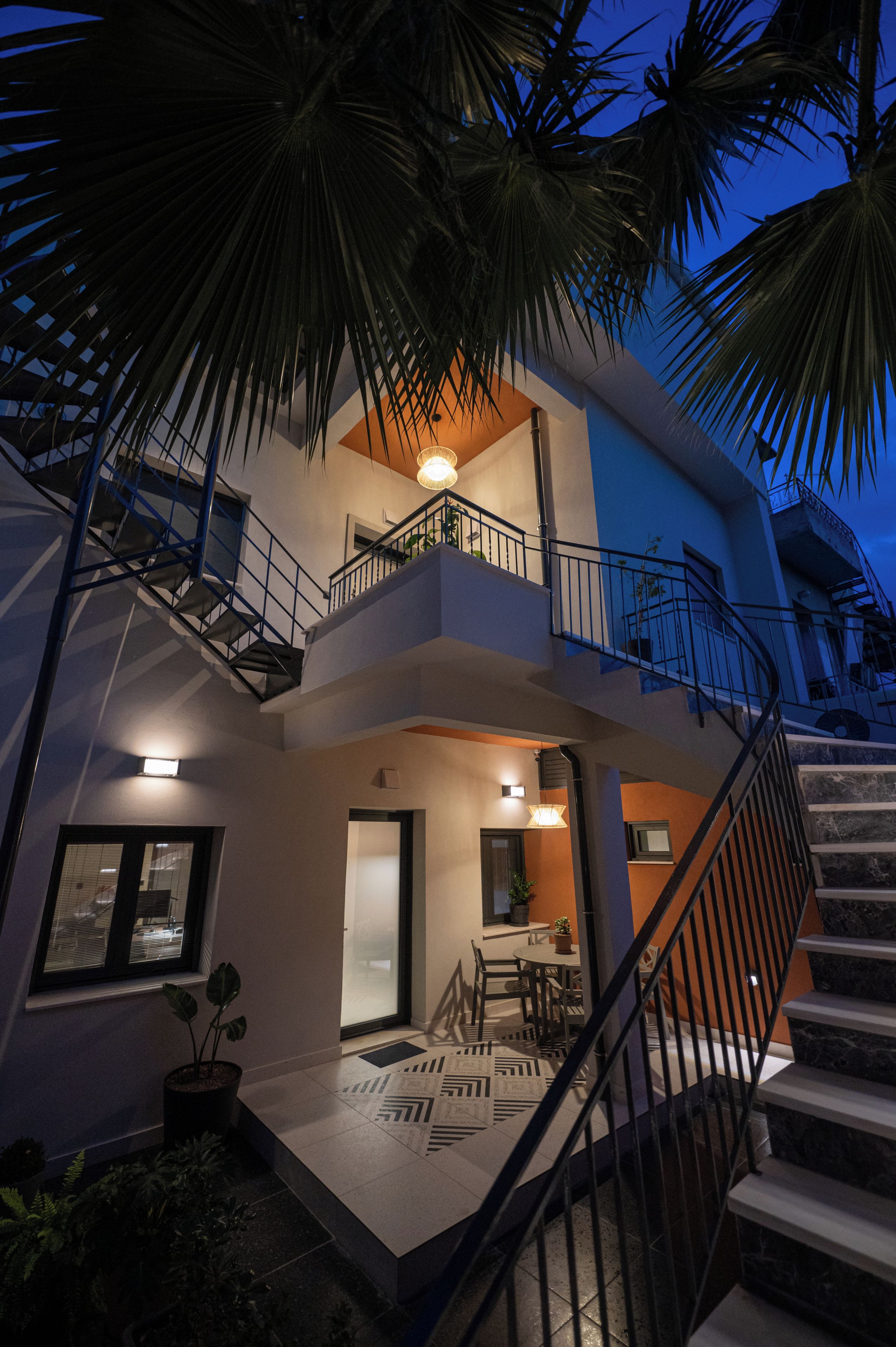 A multi-level residential building with a staircase, balcony, and outdoor seating area.