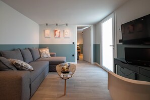 Una sala de estar moderna con un sofá, una mesa de centro, un televisor y obras de arte en la pared.