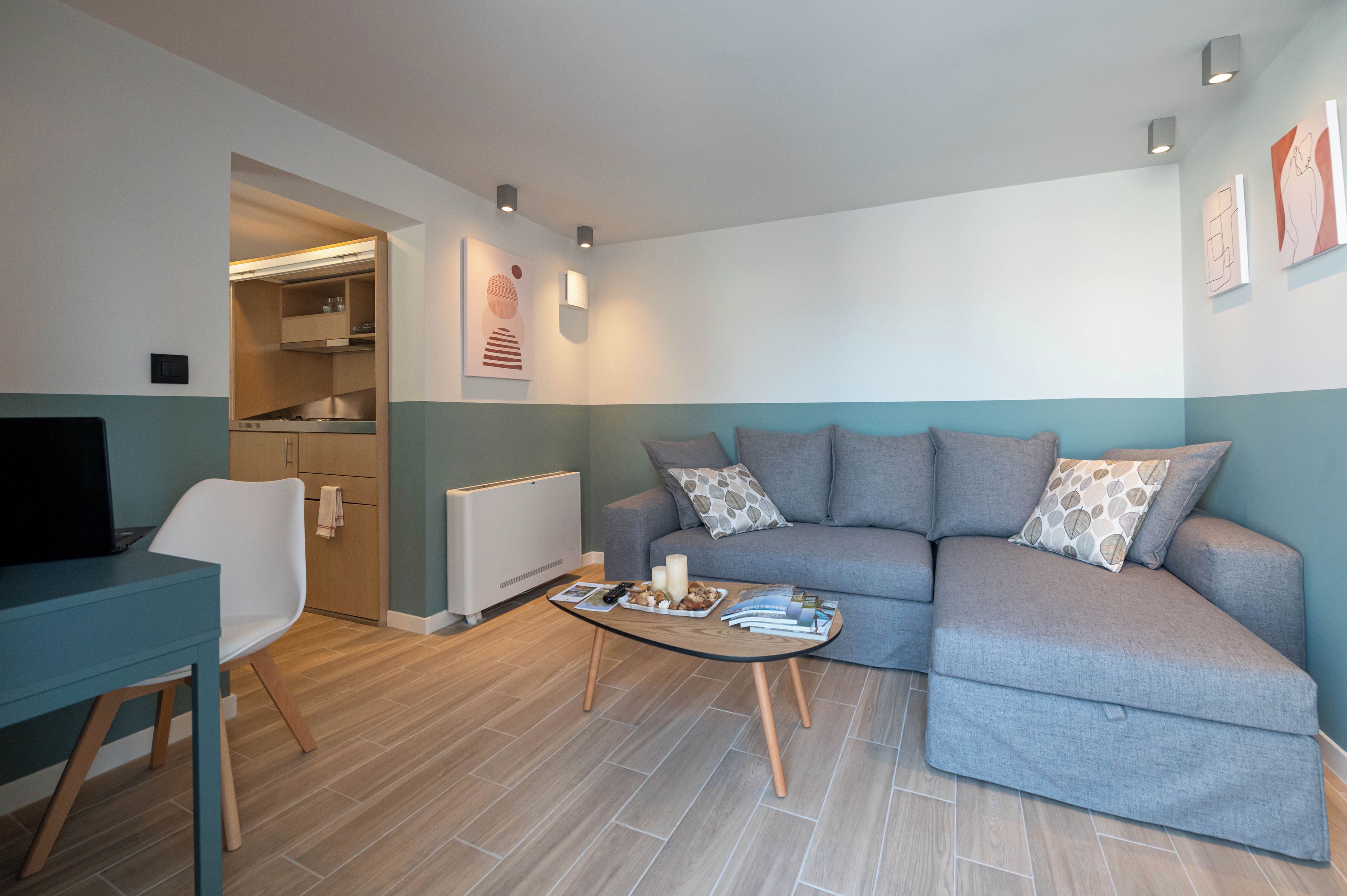 A modern living room with a sofa, a coffee table, a TV, and a kitchen area.