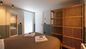 Ett hotellrum med en säng, en garderob, en spegel och en dörr som leder till ett annat rum.