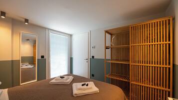Ein Hotelzimmer mit Bett, Schrank, Spiegel und einer Tür zu einem anderen Raum.