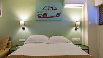 A hotel room with a bed, two nightstands, a wall-mounted lamp, and a wall painting of a car.