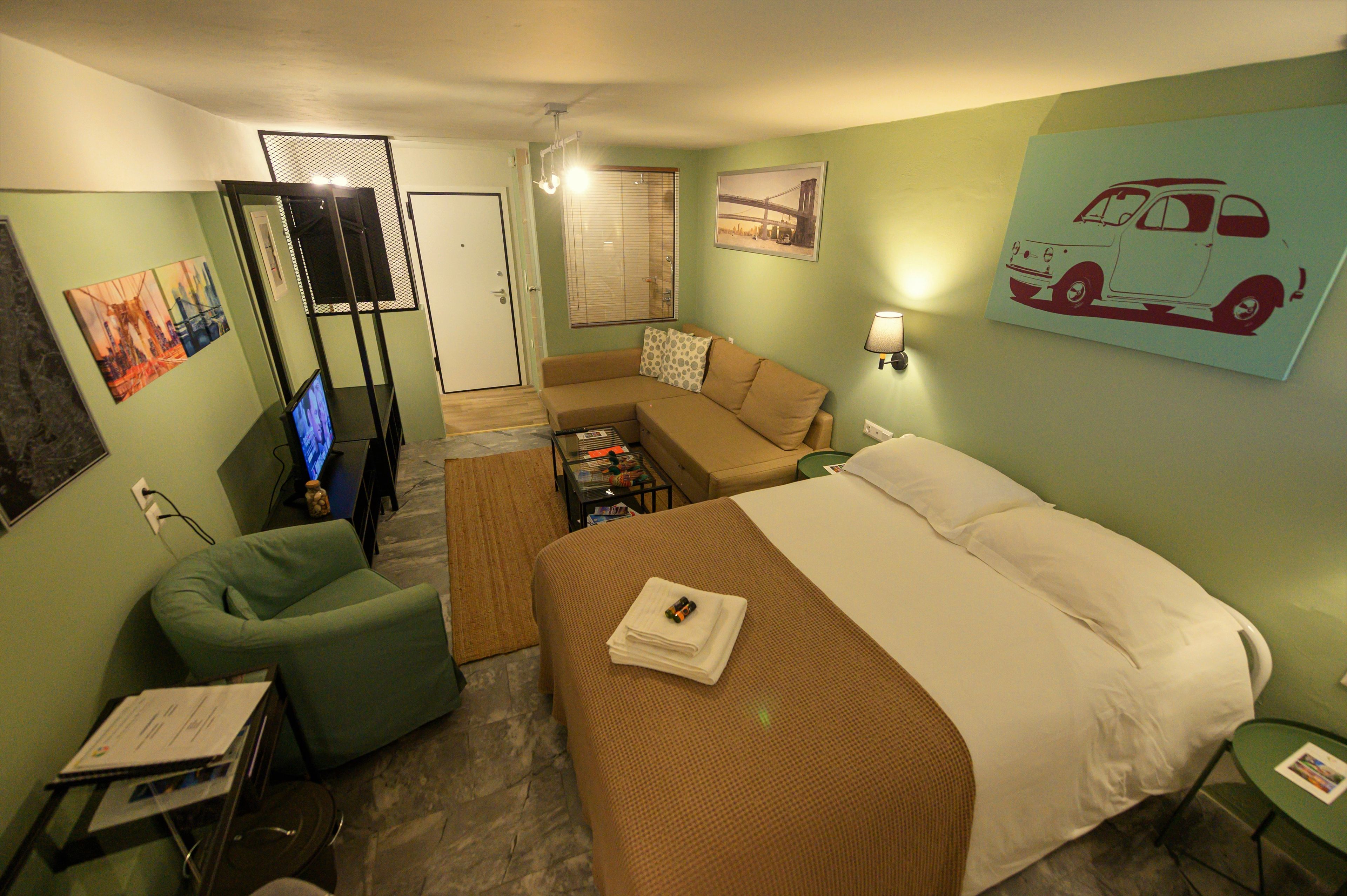 Ein Hotelzimmer mit Bett, Sofa, Fernseher und Schreibtisch mit Computer.