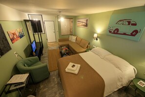 A hotel room with a bed, a sofa, a TV, and a desk with a computer.