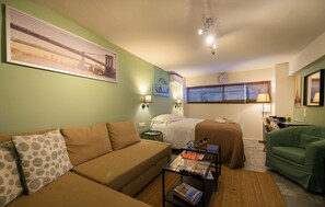 A room with a bed, a sofa, a coffee table, and a chair.