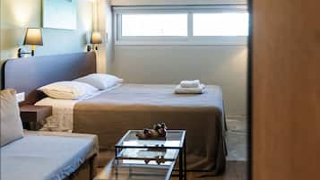 Een hotelkamer met twee bedden, een bank, een glazen salontafel en een wandklok.