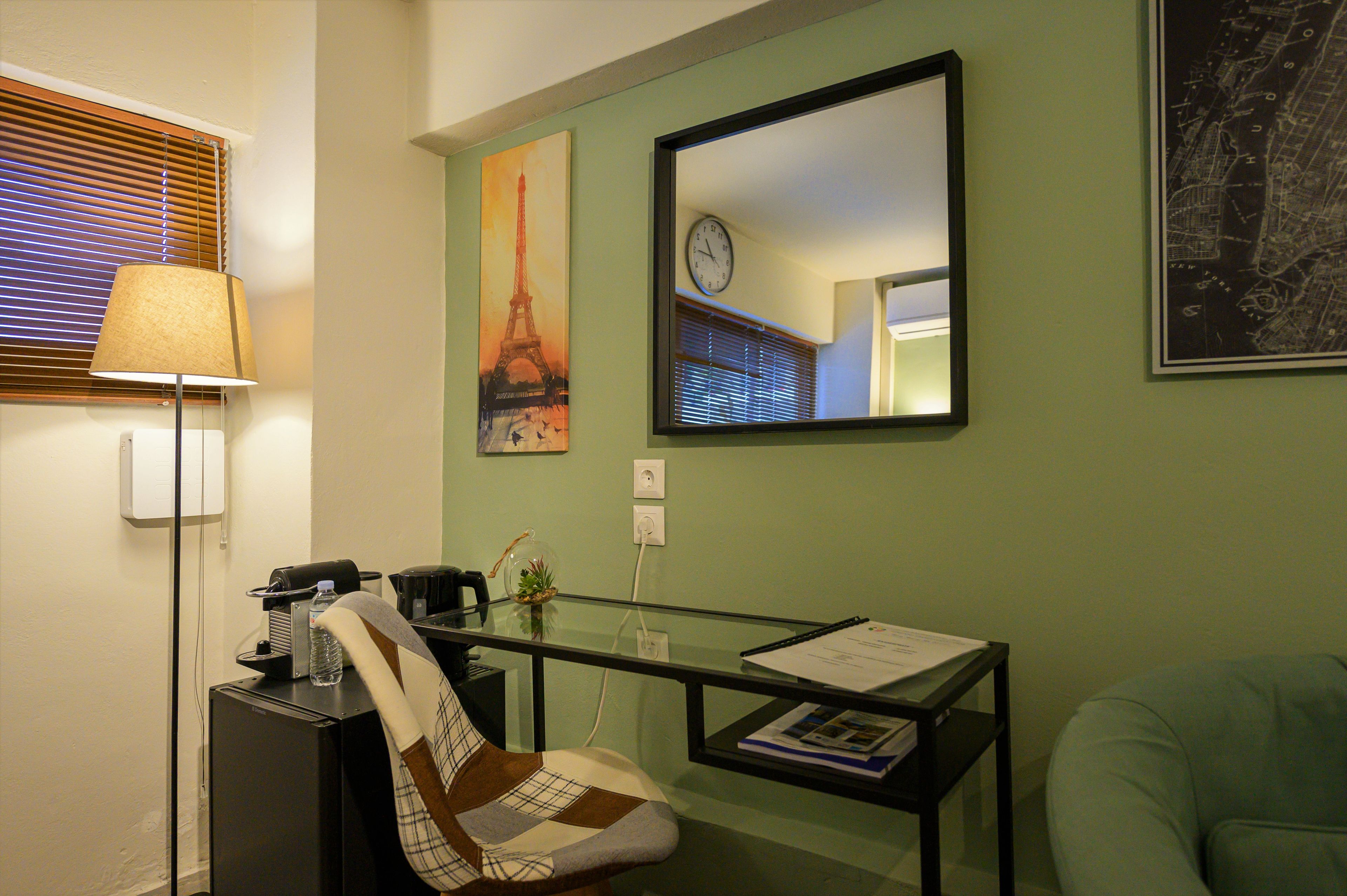 A room with a desk, chair, lamp, and wall art including a clock and a map.