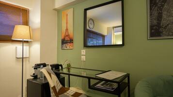 A room with a desk, chair, lamp, and wall art including a clock and a map.