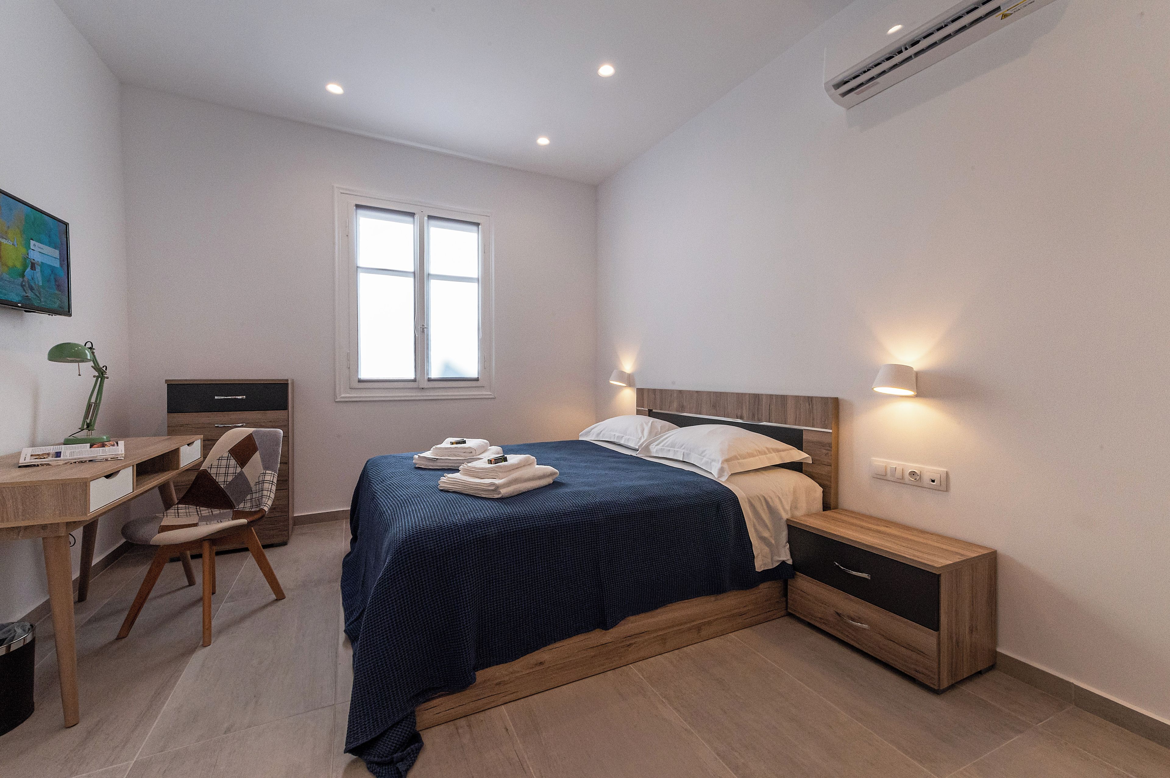 Une chambre à coucher avec un lit, des tables de chevet, un bureau et une chaise.