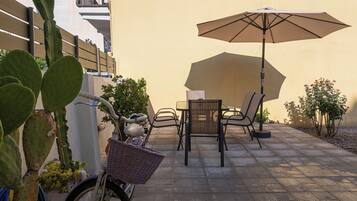 Un patio con una mesa, sillas, una bicicleta y una planta de cactus.