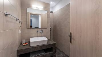 Une salle de bain moderne avec un lavabo rectangulaire, un miroir au-dessus et un espace douche.