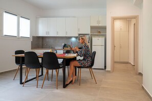 Une cuisine moderne avec des meubles blancs, une table à manger avec des chaises et un réfrigérateur.