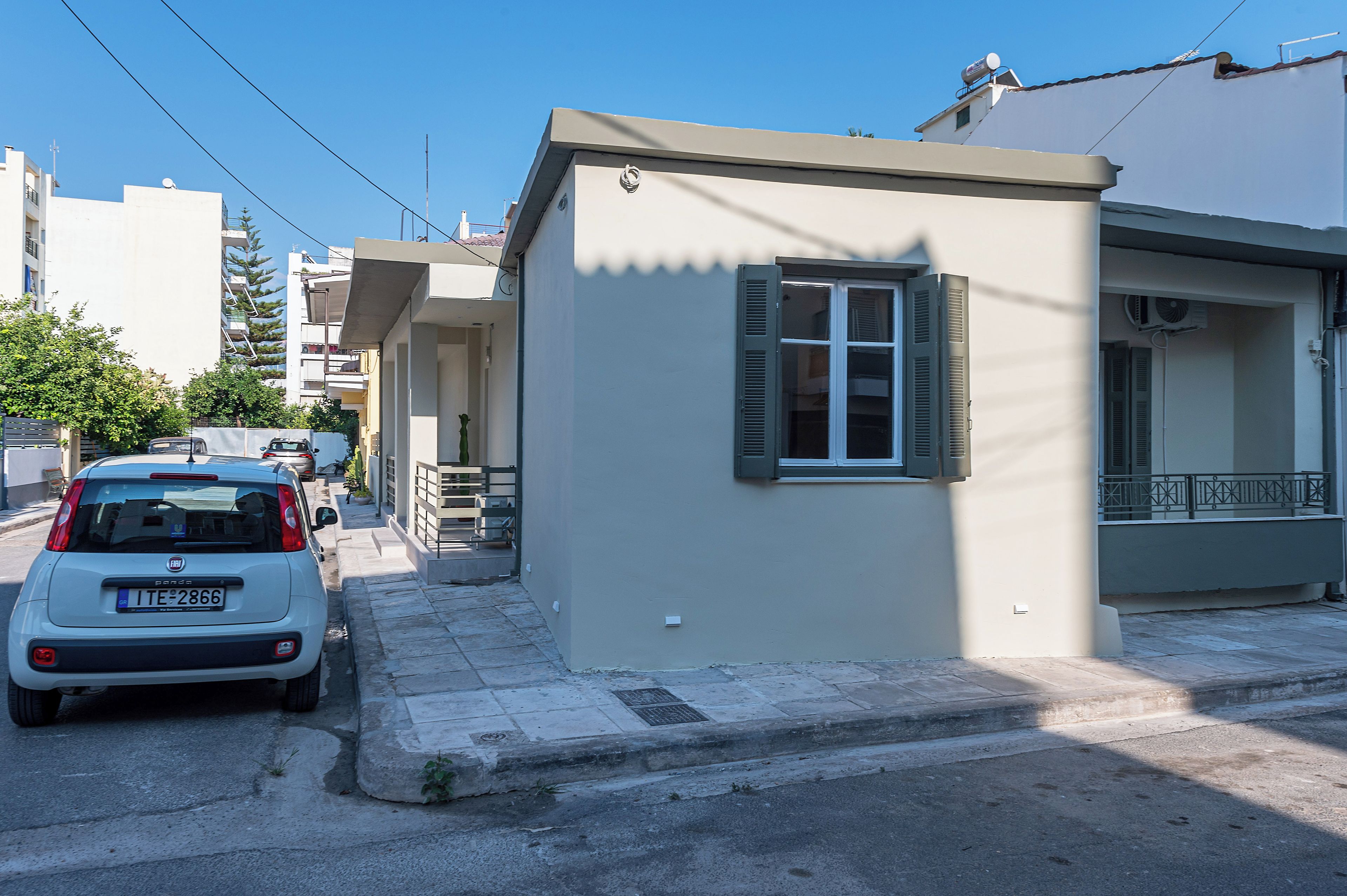 Un immeuble résidentiel avec un petit porche à l’avant et une voiture garée.