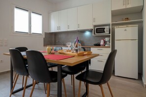 Eine moderne Küche mit weißen Schränken, einer Mikrowelle, einem Kühlschrank und einem Essbereich mit Tisch und Stühlen.