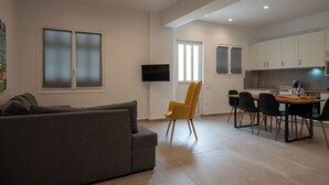 Una sala de estar moderna con un sofá gris, un sillón amarillo y un comedor con mesa y sillas.