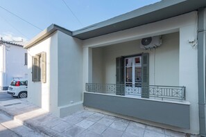 Un edificio residencial con balcón, un coche aparcado y un equipo de aire acondicionado.