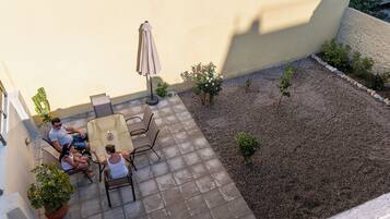 A patio with a table and chairs, a small garden area with plants, and a wall.