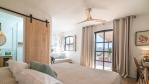 A bedroom with two beds, a wooden headboard, a ceiling fan, a desk with a chair, and a view of the outdoors. - Es Cucons Rural Hotel (Sant Antoni de Portmany)