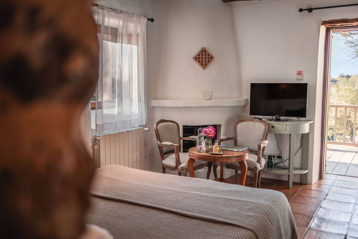 A cozy living room with a fireplace, a television, and a dining area with chairs and a table.