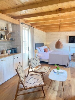 A cozy cabin-style room with a bed, a dining area, and a kitchen. - Es Cucons Rural Hotel (Sant Antoni de Portmany)
