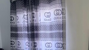 Makuuhuoneessa on sänky, vaatekaappi ja Gucci-kuviollinen verho.