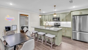 A modern kitchen with a central island, stainless steel appliances, and pendant lighting. - Downtown Access | Spacious | Family Space (Starkville)