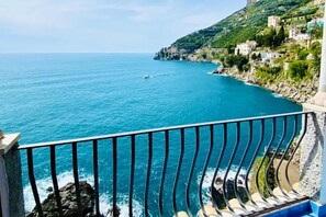 A coastal view with a balcony overlooking the sea, rocky coastline, and buildings on a hillside. - Idillioravello - Casa con 1 Camera da Letto (Marmorata)