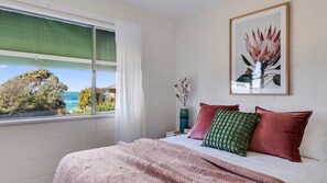 Ein Schlafzimmer mit einem Bett, einem Fenster mit Blick und einem gerahmten Bild an der Wand.