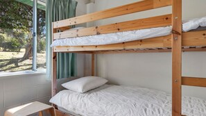 A bunk bed with a white mattress and pillow, a small wooden stool, and a window with curtains. - Beach House On Booth ~ The Quintessential Beach House for the Family Get-away (Narrawallee)