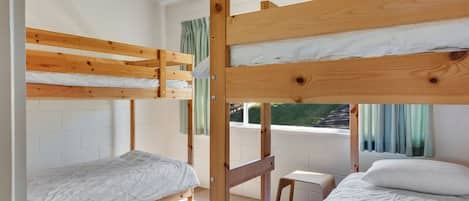 A bunk bed room with a window, a small table, and a chair.