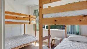 Habitación con literas, una ventana, una mesita y una silla.