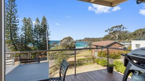 A balcony with a view of the ocean, a barbecue grill, and a wooden deck. - Beach House On Booth ~ The Quintessential Beach House for the Family Get-away (Narrawallee)