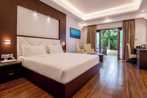 A hotel room with a large bed, a desk, a chair, and a view of the outdoors.