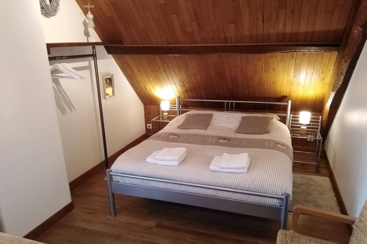 Une chambre confortable avec un lit, des lampes de chevet et un plafond en bois.
