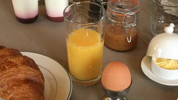A breakfast table with a croissant, coffee, orange juice, and various condiments.