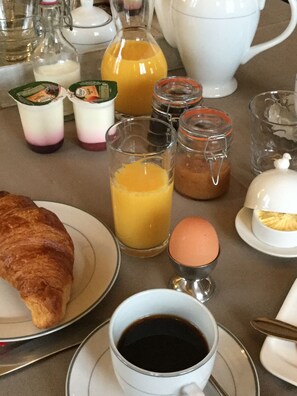 A breakfast table with a croissant, coffee, orange juice, and various condiments. - Domaine du Mas Naut (Conques-en-Rouergue)