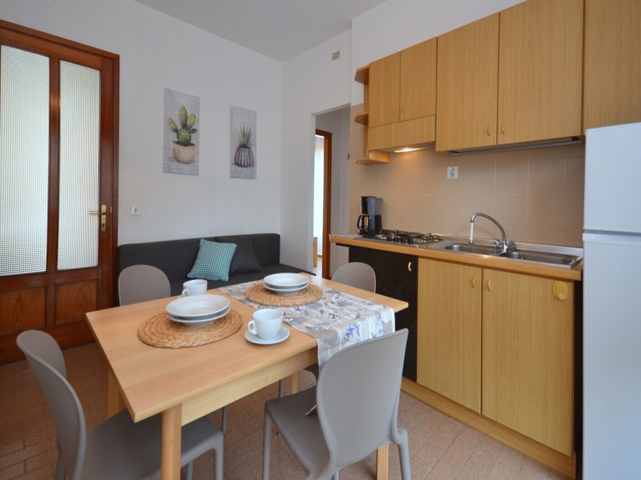 A compact kitchen with wooden cabinets, a dining table with chairs, and a small coffee station.