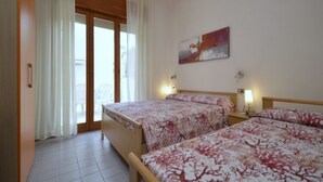 A hotel room with two beds, a large window with curtains, a painting on the wall, and a tiled floor. - Comfy apartment in the city center (Bibione)