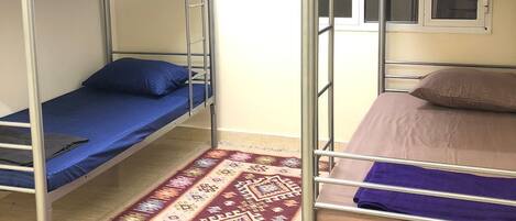Une chambre de dortoir avec des lits superposés, un tapis à motifs et une fenêtre donnant sur un paysage agréable.