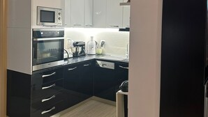 A modern kitchen with black and white cabinetry, a built-in microwave, oven, and a coffee maker on the countertop.