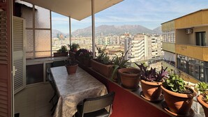 A balcony with a table and chairs, potted plants, and a city view.