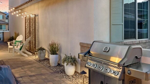A patio with a grill, outdoor seating, and decorative lights. - Desert Escape | Private Fire Pit & Pool Bliss (La Quinta)
